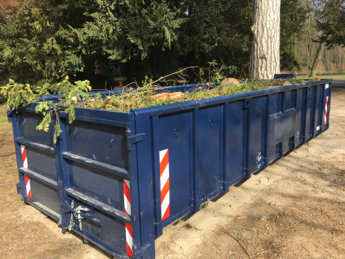 Blue,roll,off,container,filled,with,green,waste,(branches,,leaves)